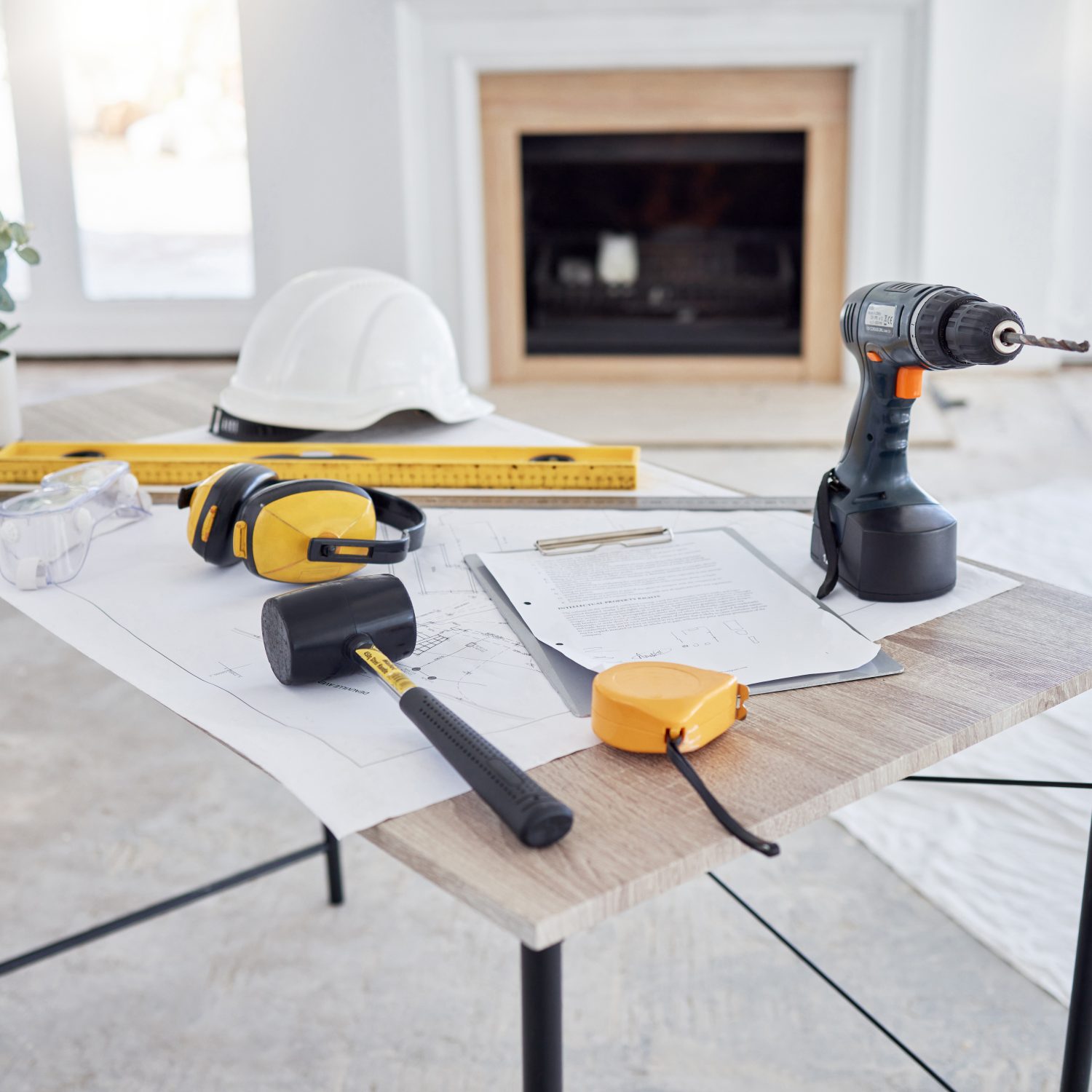 Shot of building plans and equipment on a table in an empty living room during the day.